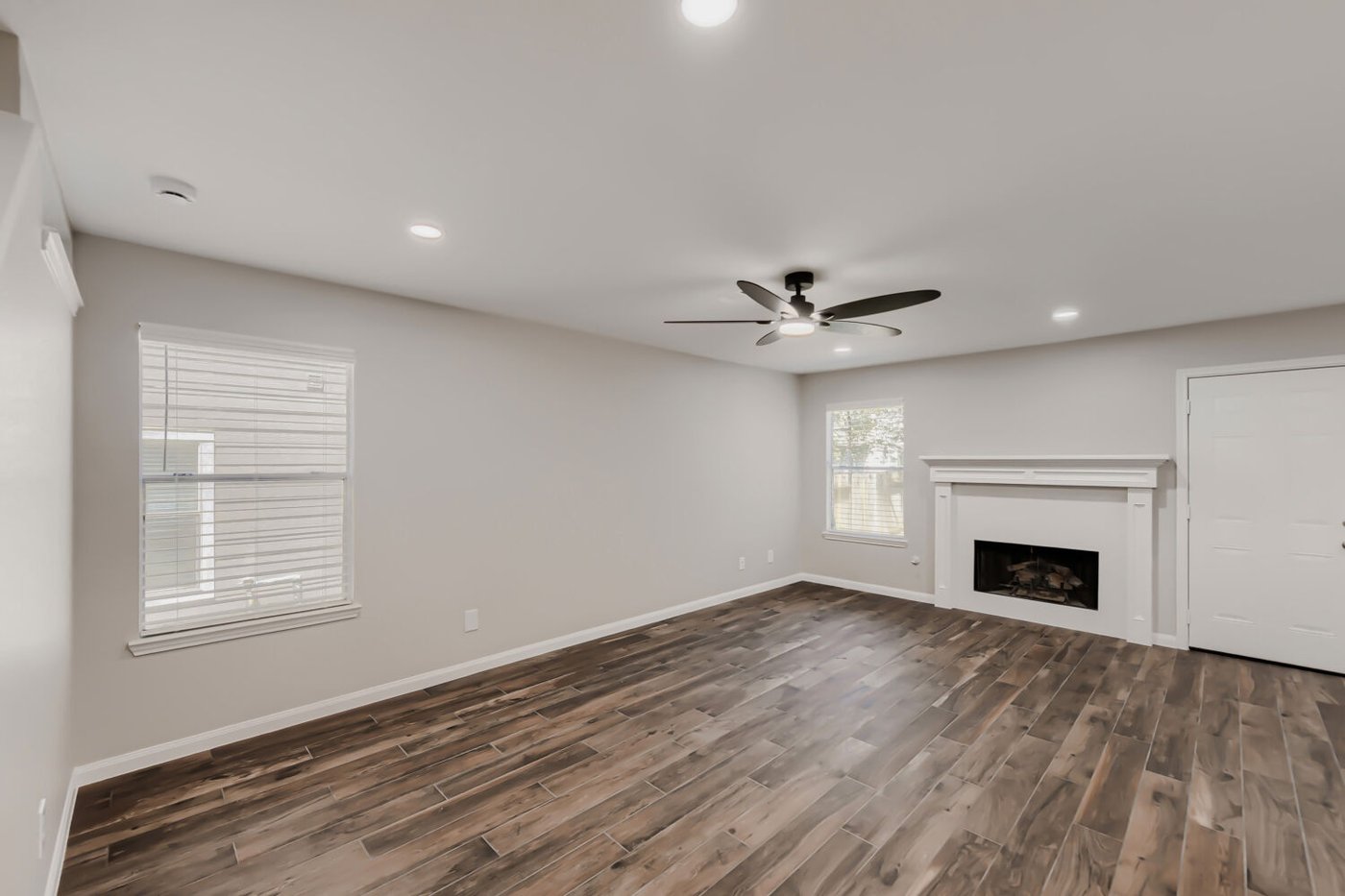 Open concept living room with a fireplace and wood look flooring at 11 Wineberry Pl, The Woodlands