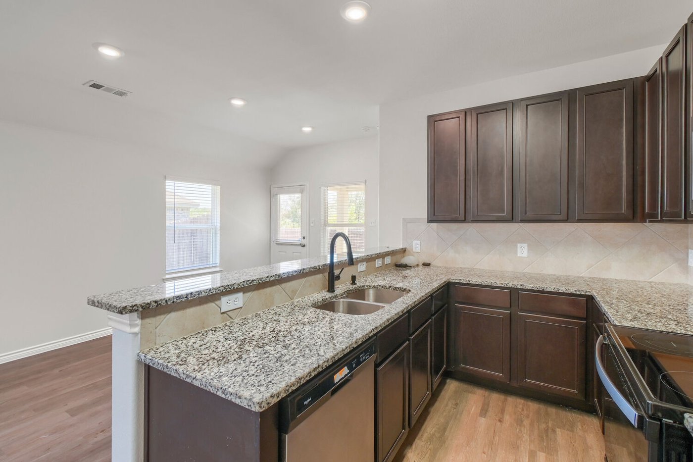 Granite island with tile backsplash in the kitchen at 1309 Fantail Ln, Ennis