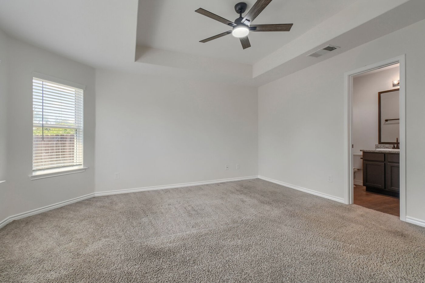 Carpeted primary bedroom with numerous windows at 1309 Fantail Ln, Ennis