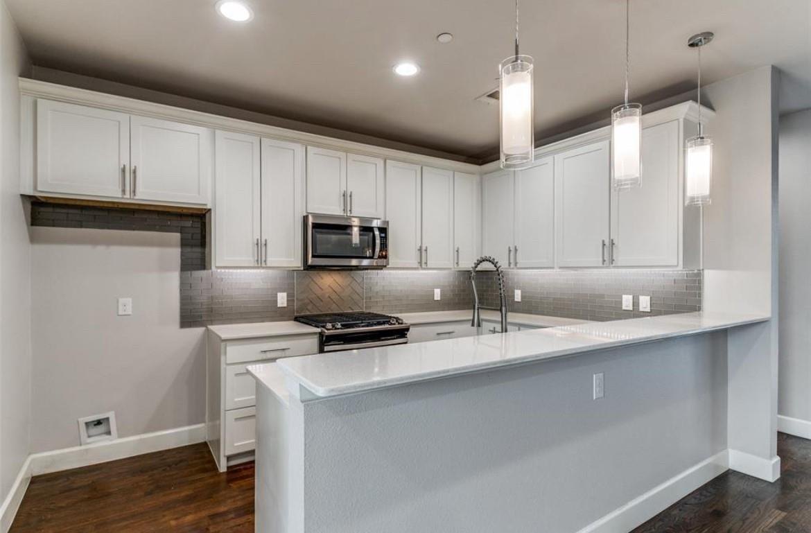 Kitchen and breakfast bar with white cabinetry at 2016 N Fitzhugh Ave #104, Dallas