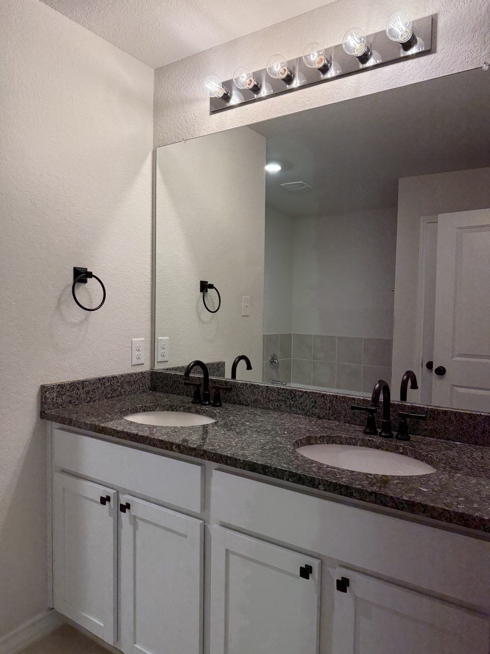 Primary bathroom with double vanities and granite counters at 22126 Backspin, San Antonio
