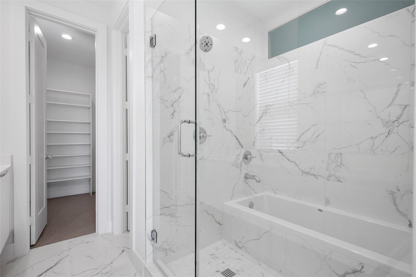 Primary bath with a marble tiled walk in shower and soaking tub at 4904 Lexington Ct, Dallas