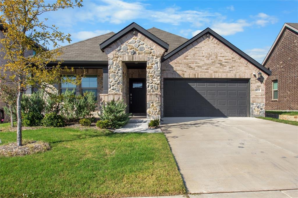 Front exterior of 614 Martell Rd, a one story brick and stone home with a 2 car garage for lease in Lowry Crossing, TX